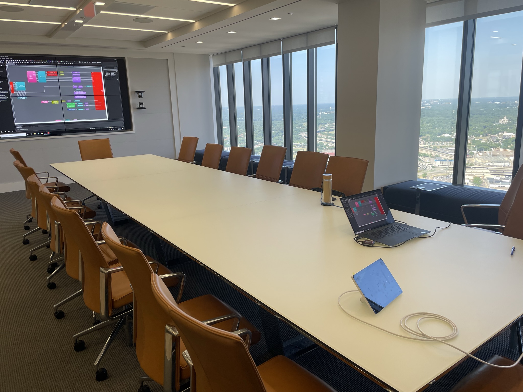 Conference room with video wall, control laptop, and table technology.