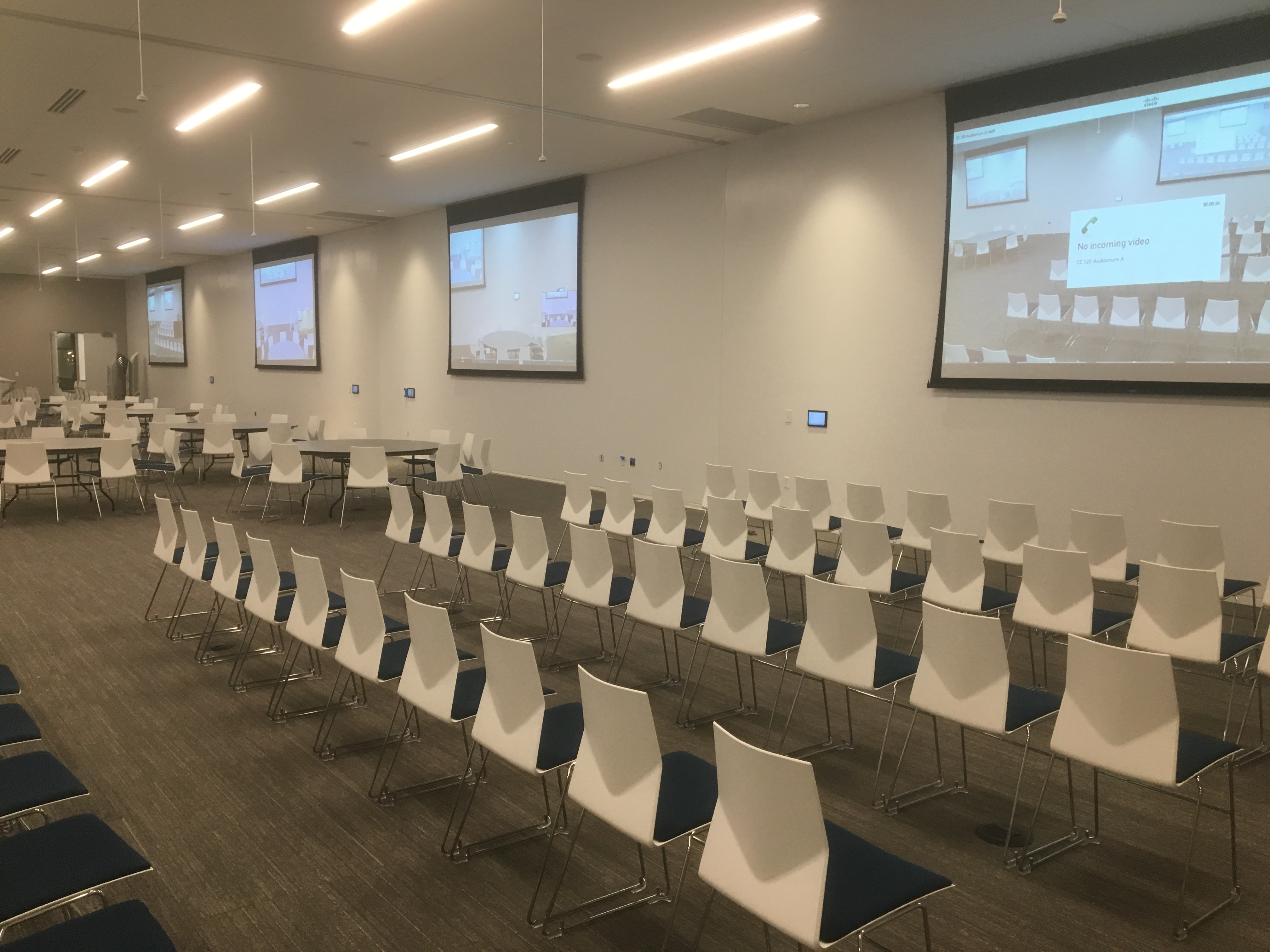 Large divisible presentation room with multiple projection screens.